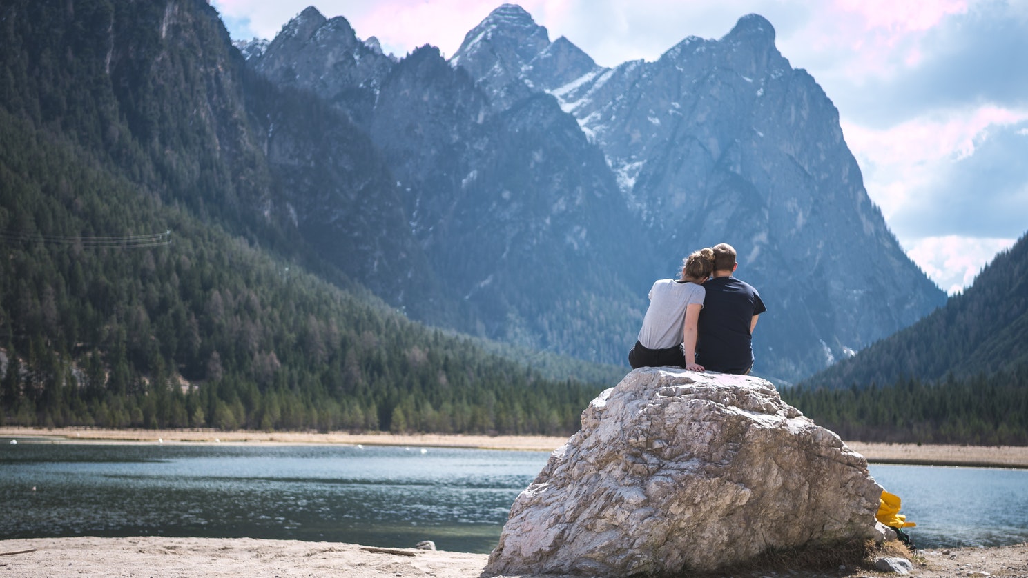 Casal em uma pedra admirando a paisagem em sua lua de mel na Europa