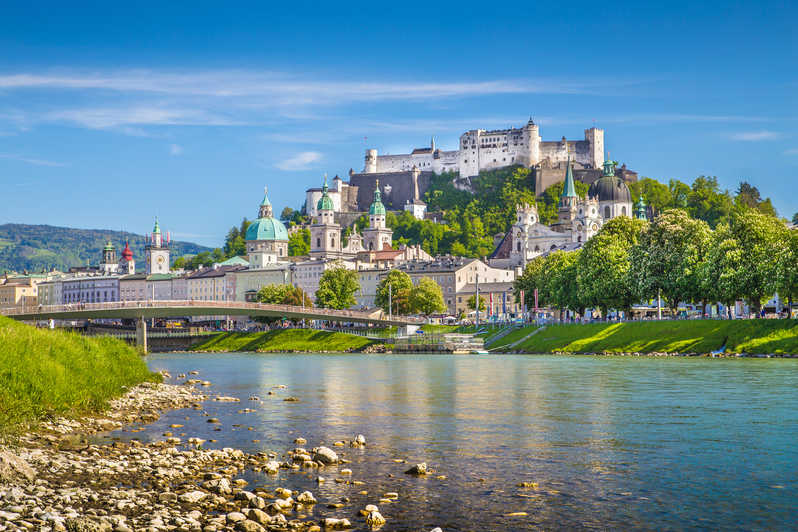 Salzburgo com um lago, uma ponte e construções medievais, cidade ideal para uma excursão para a Europa